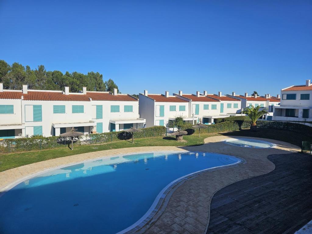 een groot zwembad voor sommige gebouwen bij Prainha Townhouse by the Sea in Alvor