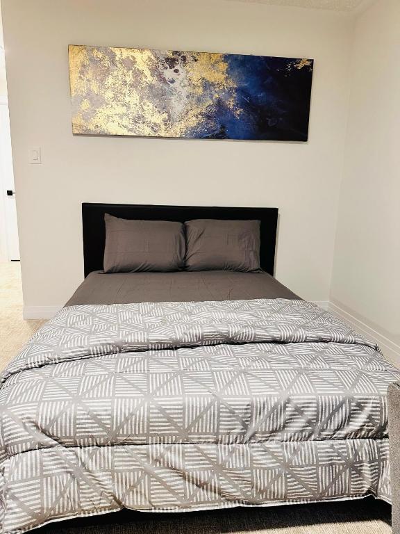a bed in a bedroom with a painting on the wall at Private and spacious Basement in Kitchener