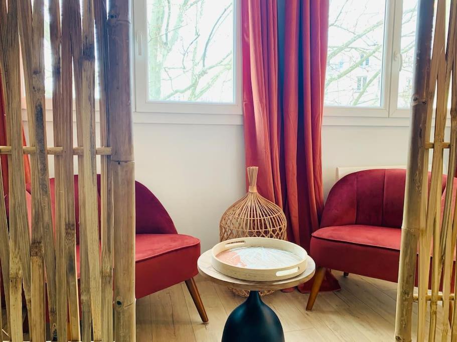 - un salon avec deux chaises rouges et une table dans l'établissement Ile verte entre CHU & vieille ville, à Grenoble
