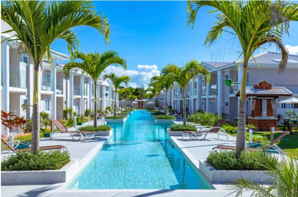 an image of a resort swimming pool with palm trees at Arraial d Ajuda - Casa Oásis - Residencial Monte das Oliveiras in Porto Seguro