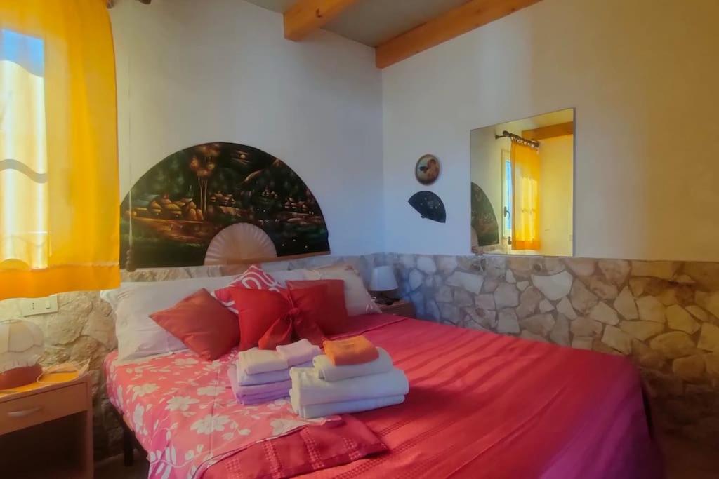 ein Schlafzimmer mit einem Bett mit roten Laken und einer Steinmauer in der Unterkunft Casetta vista mare 2 Climatizzata in Castellammare del Golfo
