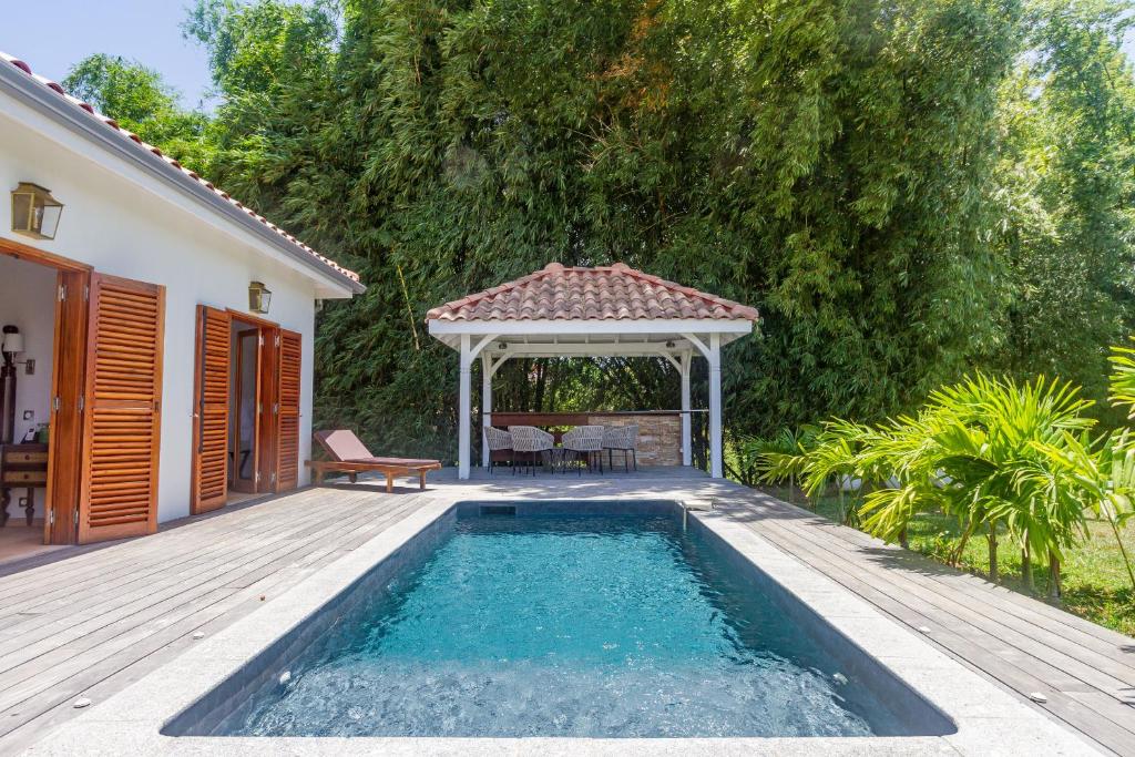 a swimming pool with a gazebo next to a house at Villa Marie - Habitation Saint Charles in Petit-Bourg