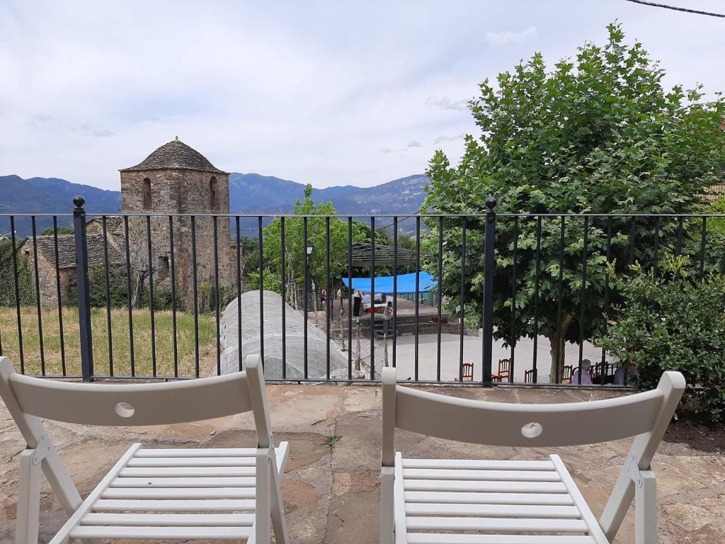 duas cadeiras brancas sentadas em frente a uma cerca em Casa Castillón em Ceresa