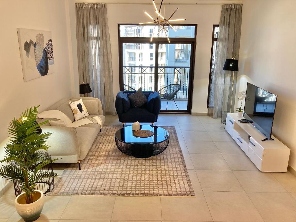 a living room with a couch and a tv at White Sage - Tranquil Haven 1BR With Burj Views in Dubai