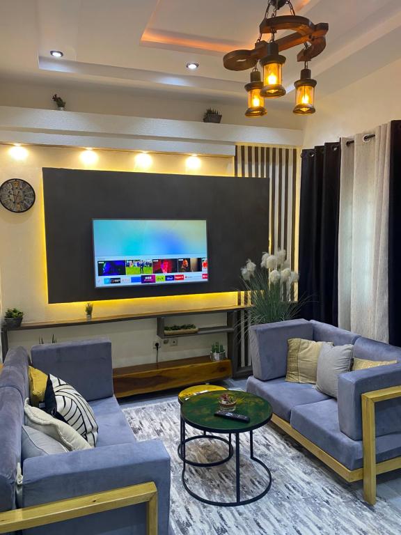 a living room with two blue couches and a tv at Emefa Room in Cotonou