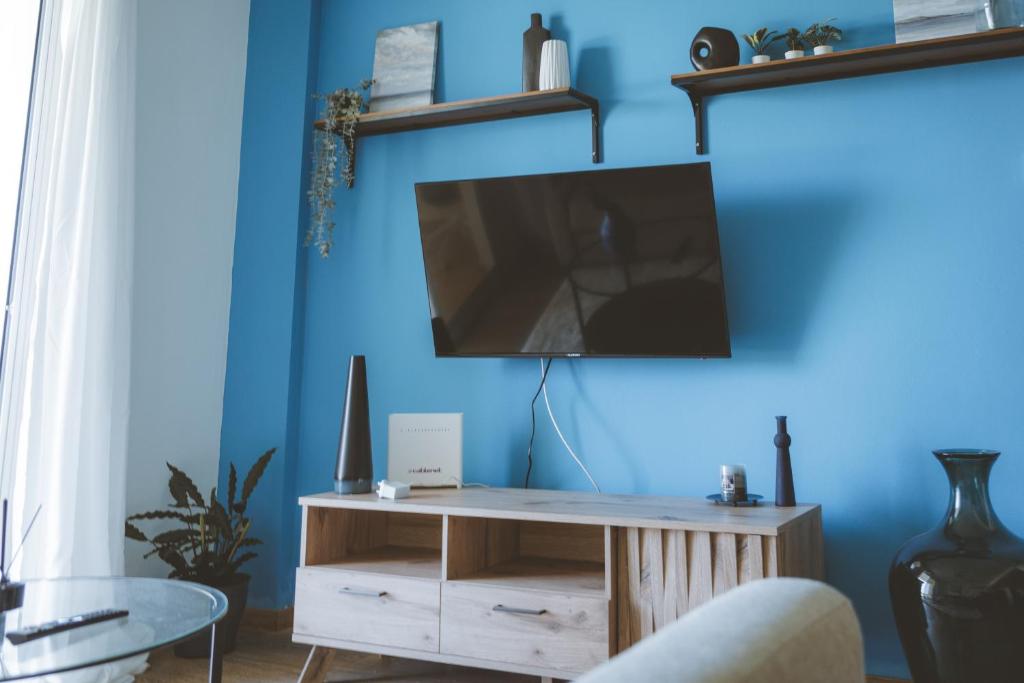 uma sala de estar com televisão numa parede azul em Blue Touch Pervolia Paradise Near The Beach em Lárnaca