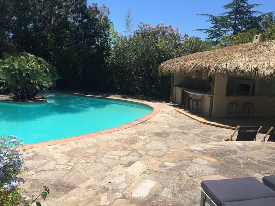 - une piscine à côté d'une maison au toit de chaume dans l'établissement Villa Saint-Côme, du grand luxe à 1 min de la mer, à Hyères