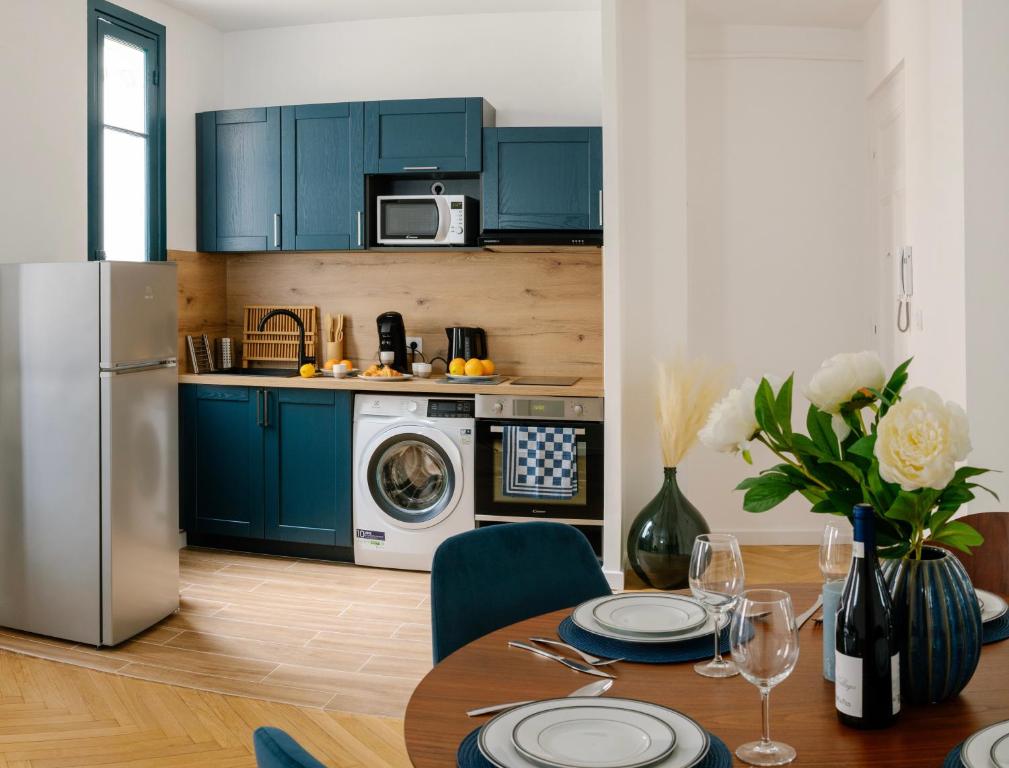 a kitchen with blue cabinets and a table and a refrigerator at Serenity chic apartment Nice center in Nice