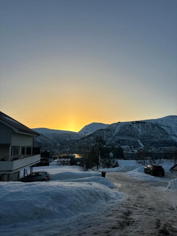 eine schneebedeckte Straße mit Sonnenuntergang in den Bergen in der Unterkunft Sentral 4-roms leilighet i Trollbakken in Tromsø