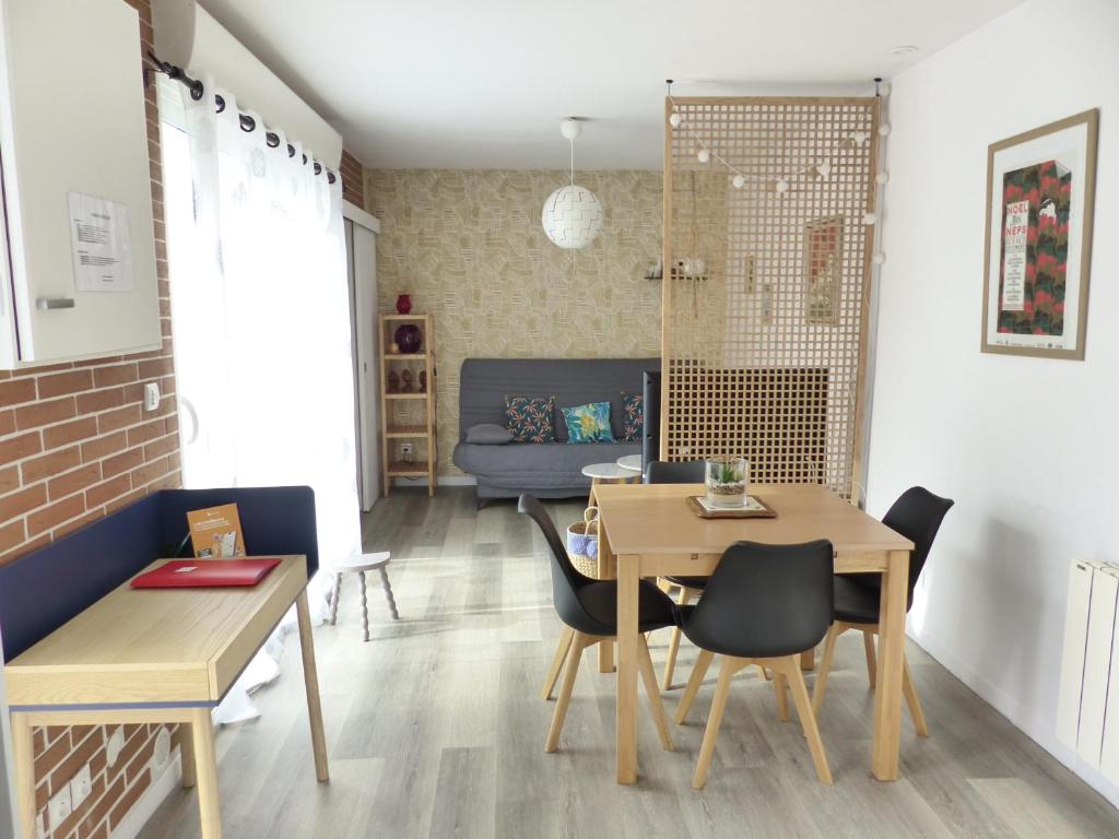 a dining room and living room with a table and chairs at LA PETITE MAISON TAHET, 2 pers avec terrasse in Basse-Indre