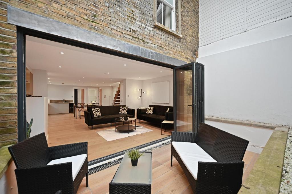 a living room with black furniture and a brick wall at Stunning 2 Bed basement flat in Hammersmith in London