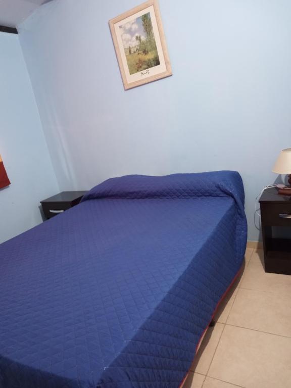 a blue bed in a room with a picture on the wall at Brisas de montaña in Las Compuertas