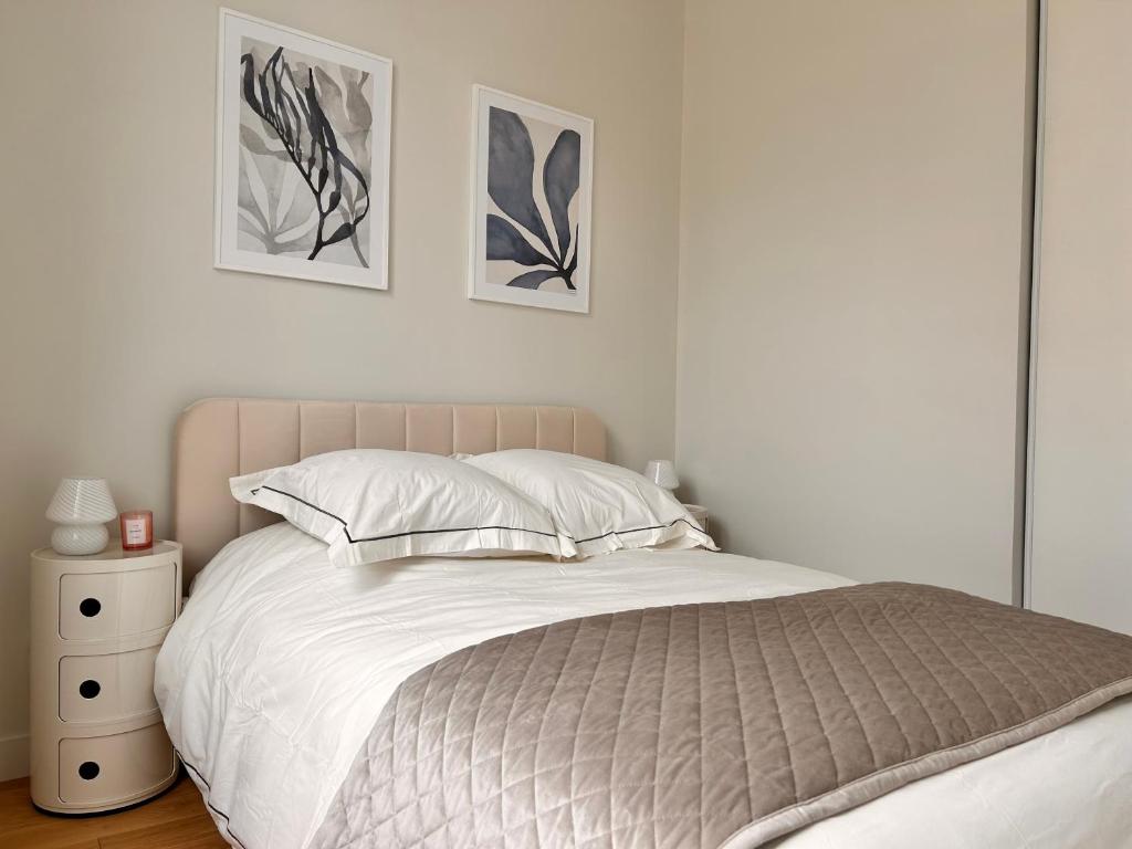 a bedroom with a bed and two pictures on the wall at Beautiful, modern 1-bed apartment, 5 mins RER A in Saint-Germain-en-Laye