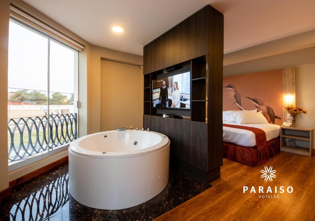 a bathroom with a tub and a bed and a television at Hoteles Paraiso PIURA in Piura