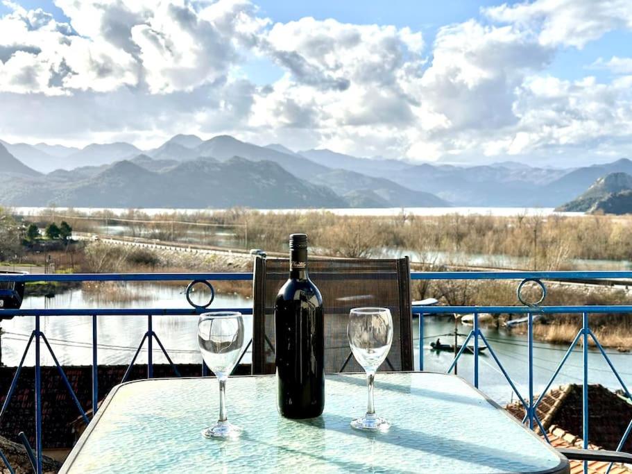 a bottle of wine sitting on a table with two glasses at Sunny balconies apartments Skadar Lake in Virpazar