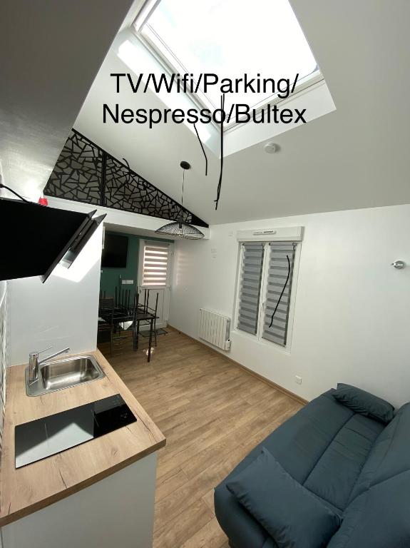 un salon avec un canapé bleu et une cuisine dans l'établissement Studio tout confort, recharge voiture électrique, à Horbourg-Wihr