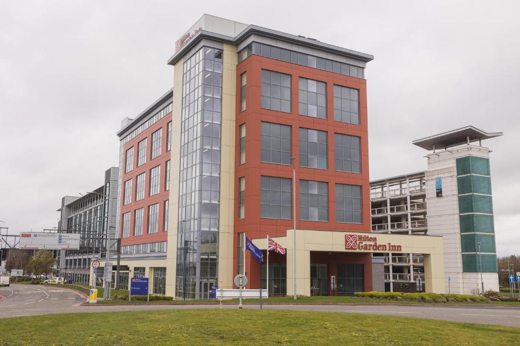 a tall red building in front of a street at Hilton Garden Inn Birmingham Airport Uk in Bickenhill