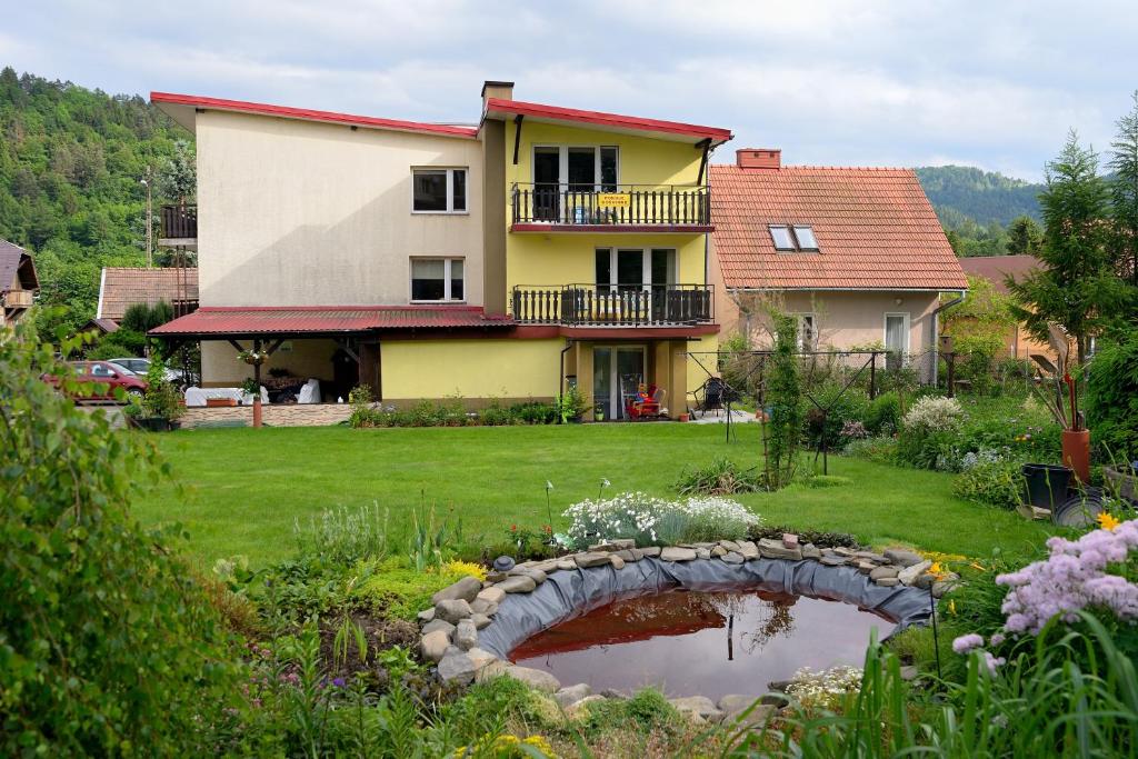 a house and a garden with a pond in the yard at Pokoje u Danuty in Piwniczna-Zdroj