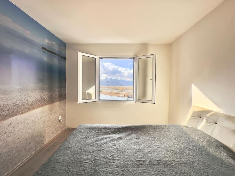 een slaapkamer met een groot bed en een raam bij JG Sunny Balcony apartment Skadar Lake in Podgorica