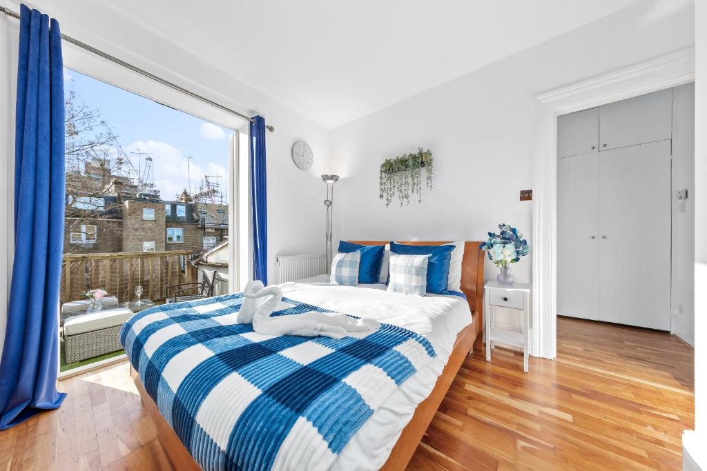 um quarto com uma cama e uma grande janela em Balcony Blue Theme 1 Bedroom Central London Luxury Flat Near Hyde Park! Accommodates up to 6! Double Sofa Bed and Next to Station! em Londres