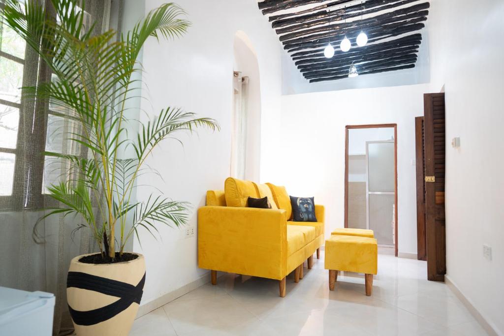 a living room with a yellow chair and a plant at Pili Pili Kahawa House in Stone Town