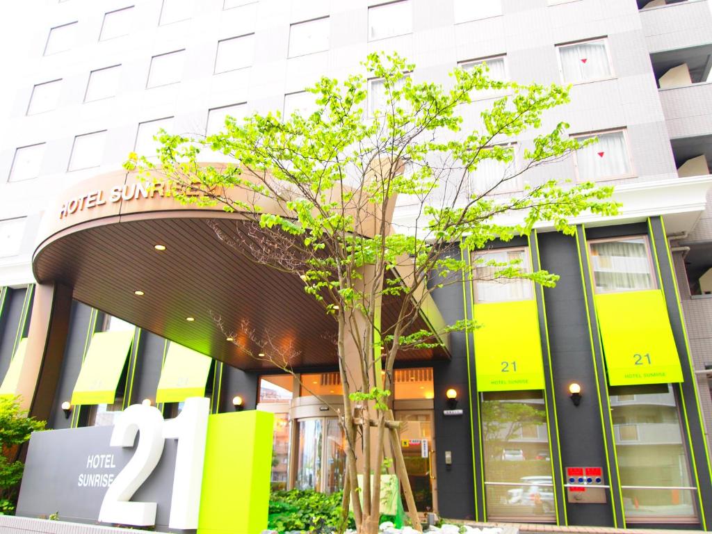 a building with a tree in front of it at Hotel Sunrise21 in Higashihiroshima