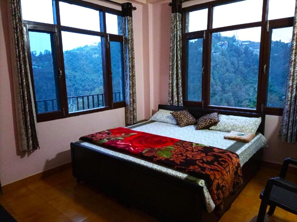ein Schlafzimmer mit einem Bett in einem Zimmer mit Fenstern in der Unterkunft Hotel Thakur Home's Mountain View - Outdoor furniture - Picnic Area in Jutogh