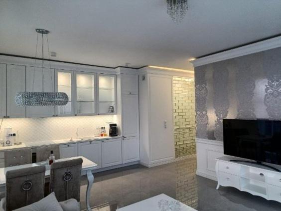 a large kitchen with white cabinets and a tv at PARAISO GLAMOUR 10B in Łukęcin