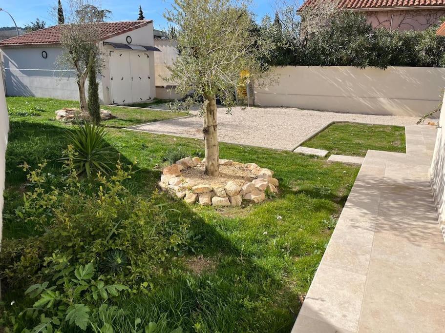 un arbre dans un lit fleuri dans une cour dans l'établissement Bas de villa avec jardin, à Martigues