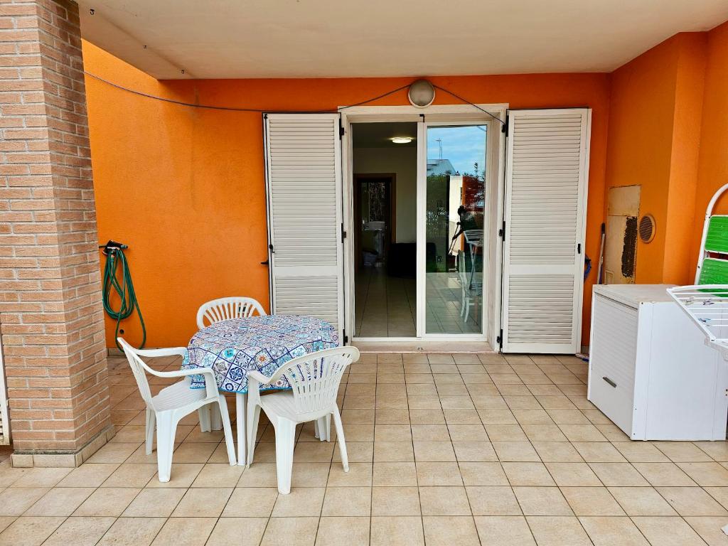 un tavolo e sedie su un patio con porta aperta di SE052 - Marotta, delizioso bilocale con giardino a Marotta
