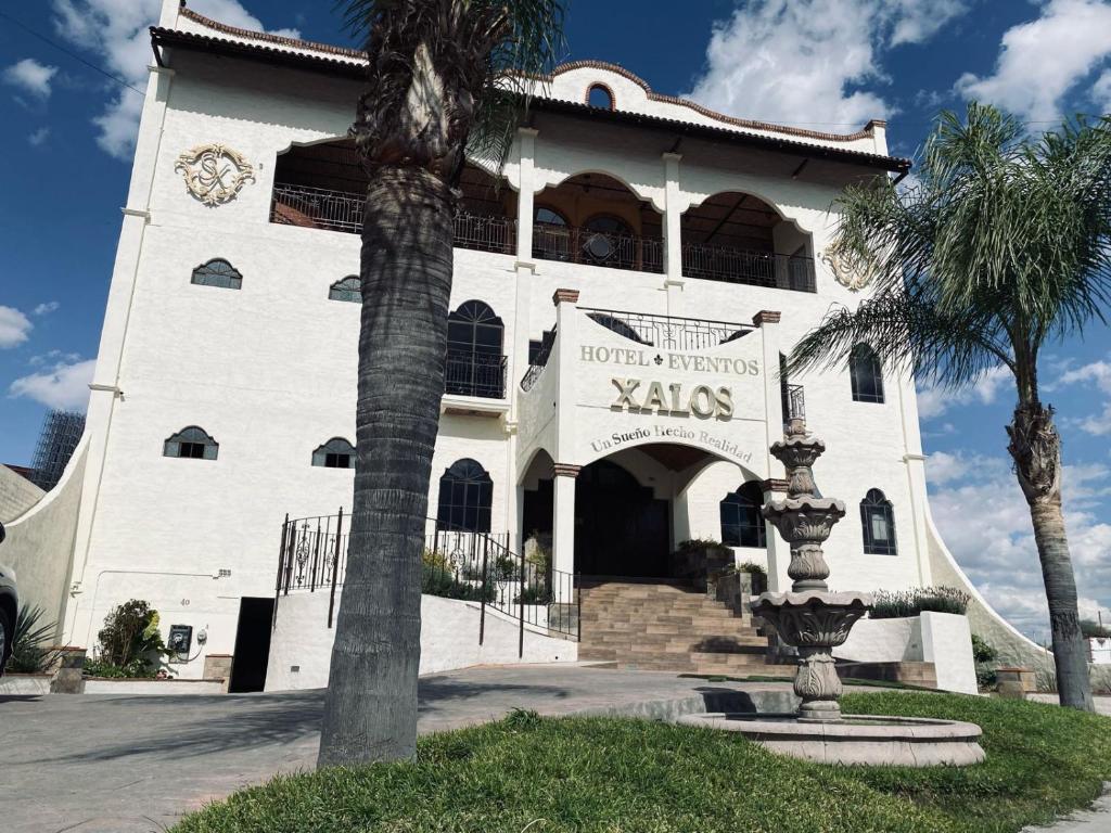 Jalostotitlán的住宿－Hotel & Eventos Xalos，一座白色的大建筑,上面有时钟