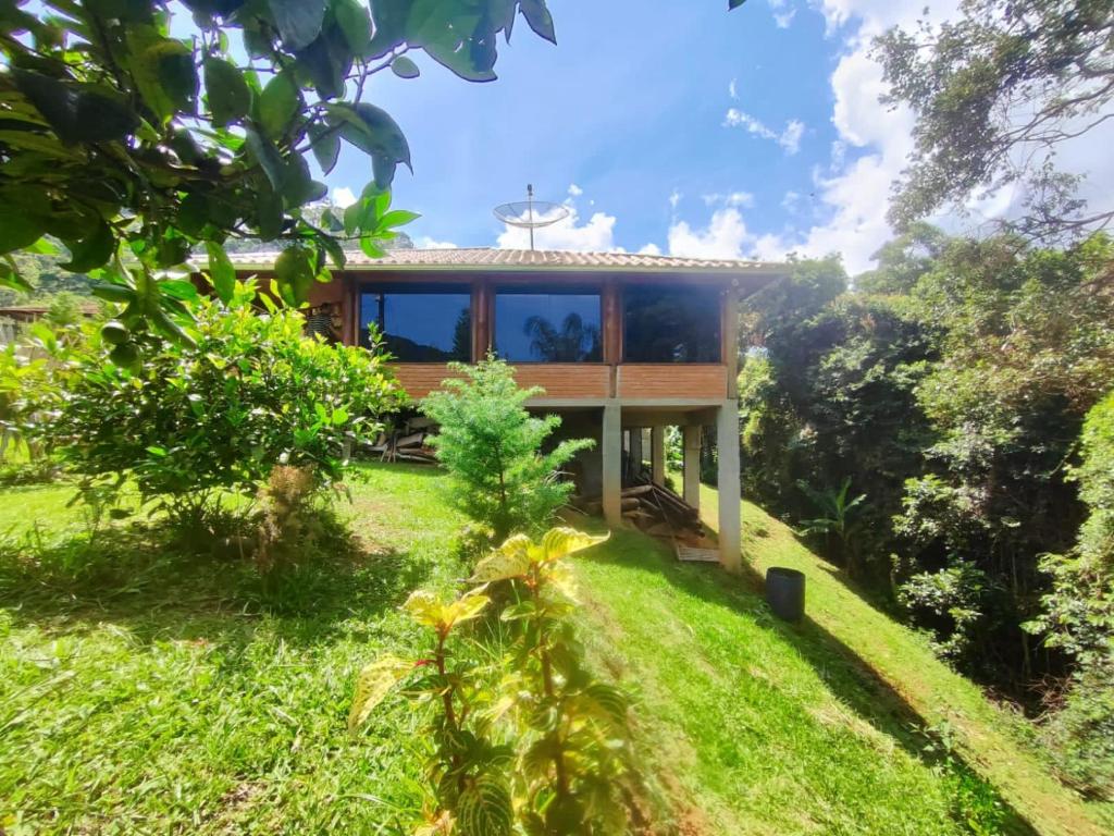 una casa en una colina con un patio verde en Chalé da Lua - Parte Alta Parque Nacional de Itatiaia, en Itamonte