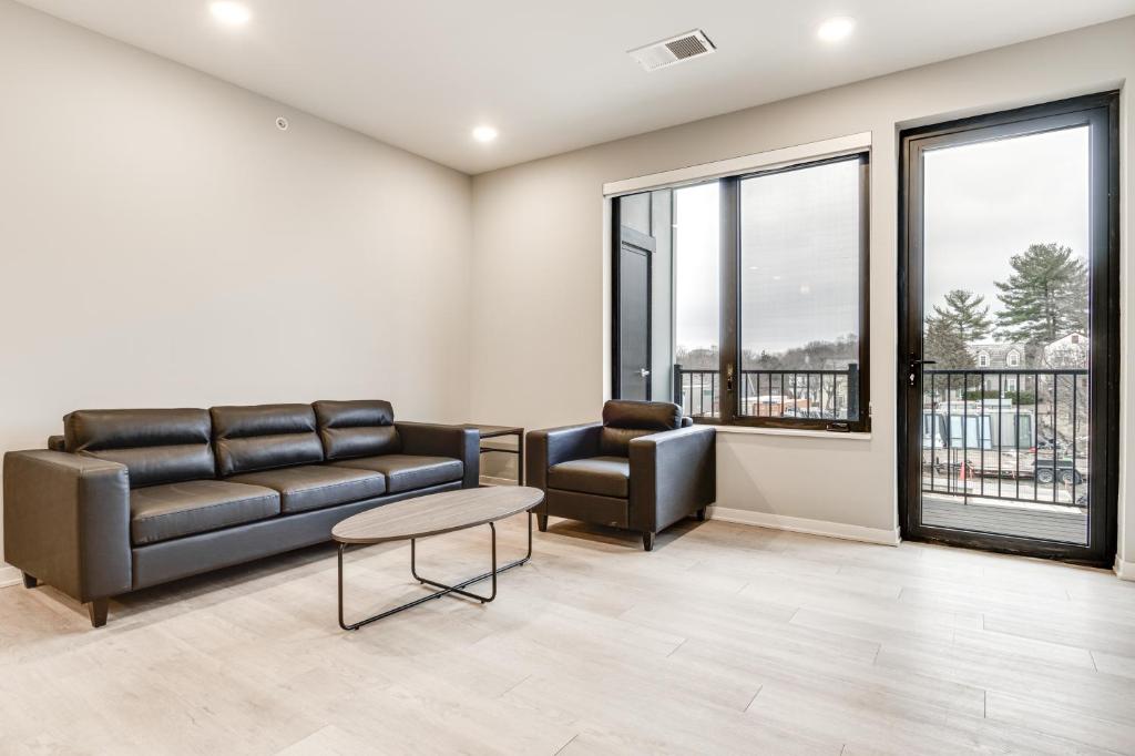 uma sala de estar com um sofá, cadeiras e janelas em Bloomington Apartment with Balcony, 3 Mi to Downtown em Bloomington