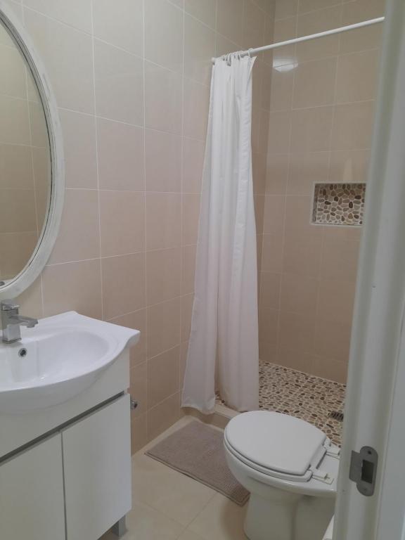 y baño con aseo, lavabo y ducha. en Tropicana guesthouse, en Ponta do Ouro