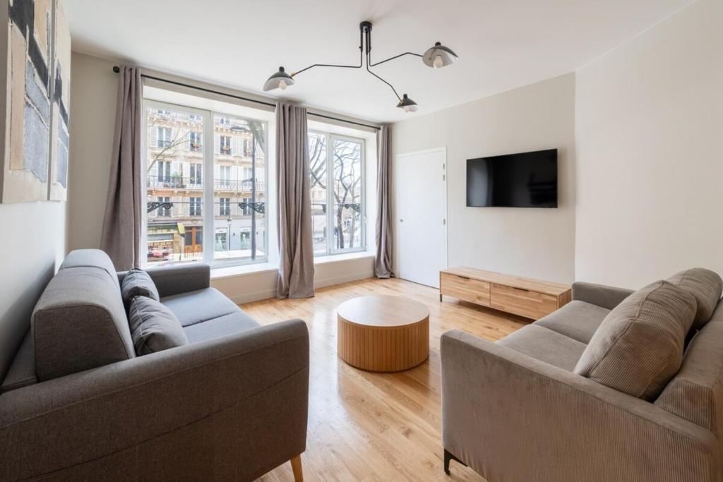 un salon avec deux canapés et une télévision dans l'établissement Beautiful & Modern 1BD Flat near Montmartre, à Paris