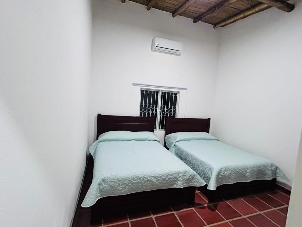 2 camas en una habitación con paredes blancas en Finca Los Canelos, en Ricaurte