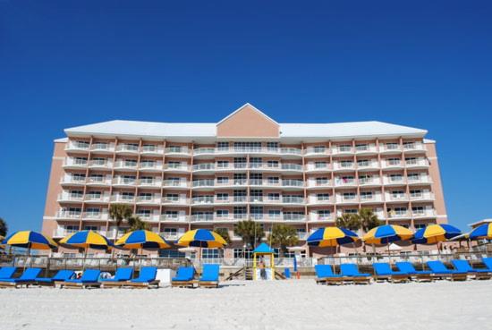 un gran hotel en la playa con sillas y sombrillas en Palmetto Beachfront Hotel, a By The Sea Resort, en Panama City Beach