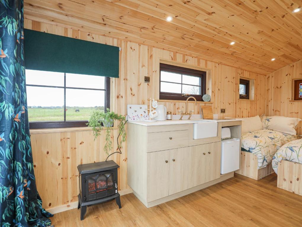a kitchen and living room in a log cabin with a stove at Tal Sarn Shepherd Hut in Llanfairpwllgwyngyll