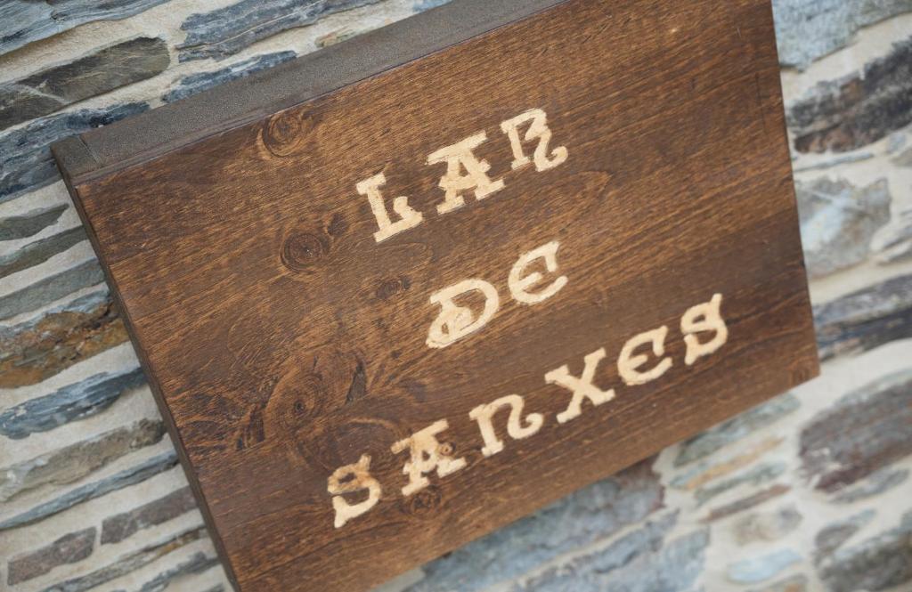 een houten bord op een stenen muur bij Casa Rural Lar de Sanxes in Lugo