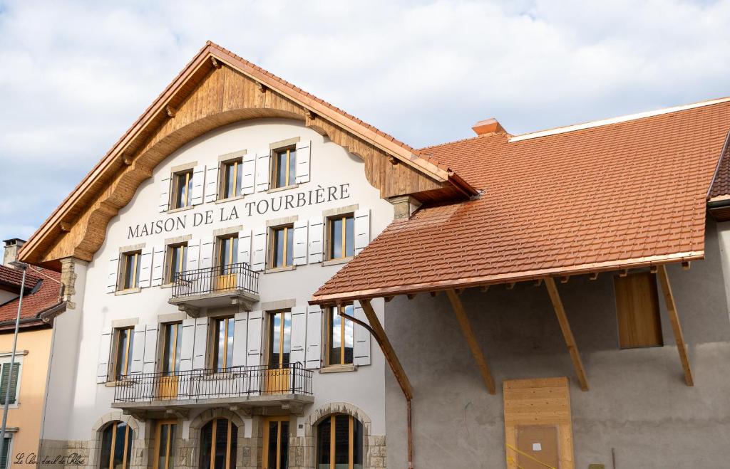 a white building with a brown roof at Hôtel-Restaurant du Cerf in Les Ponts-de-Martel