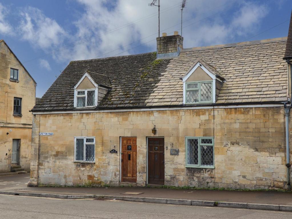 an old stone building with a brown door and windows at Mouse Hole Cottage in Cheltenham