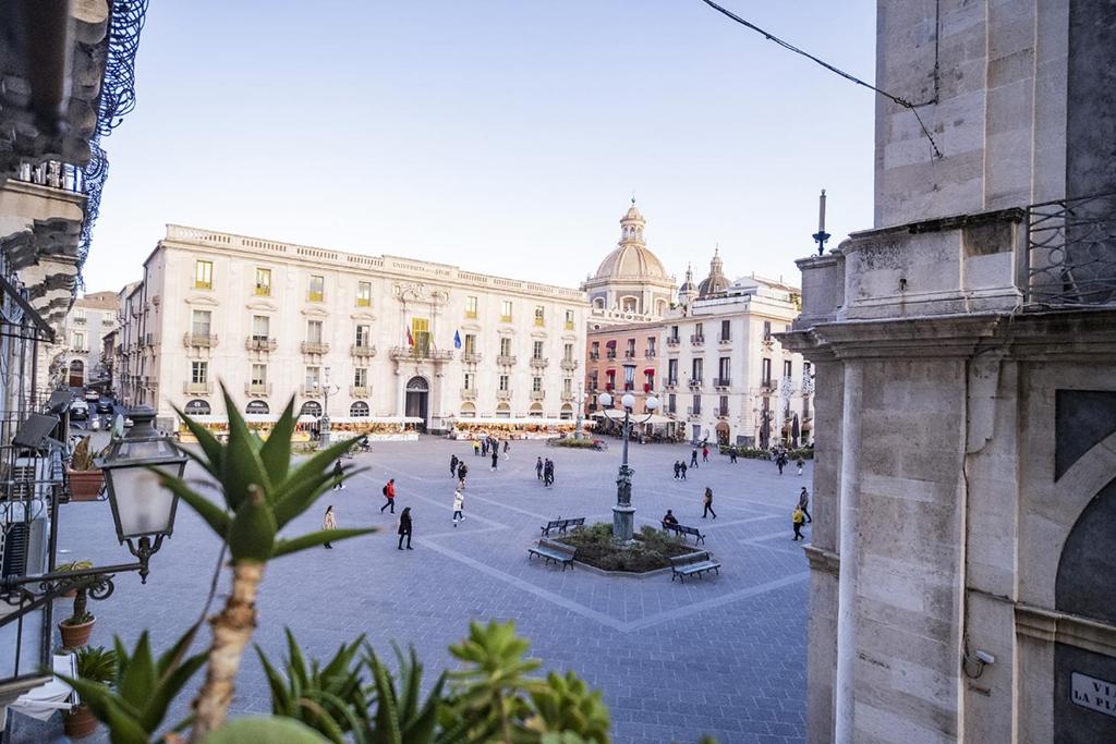 una piazza della città con persone che camminano davanti a un edificio di CHARME Catania Central Suites a Catania