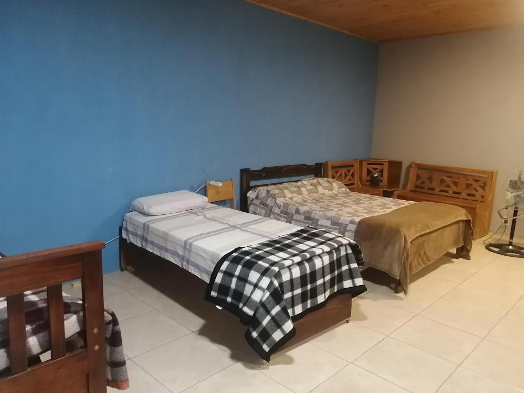 1 dormitorio con 2 camas y pared azul en Mirna, en Tranqueras