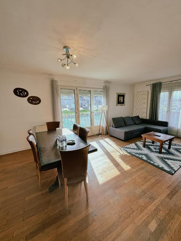 uma sala de estar com uma mesa e um sofá em Duplex avec jardin - Proche Paris - Disneyland - RER - em Noisy-le-Grand