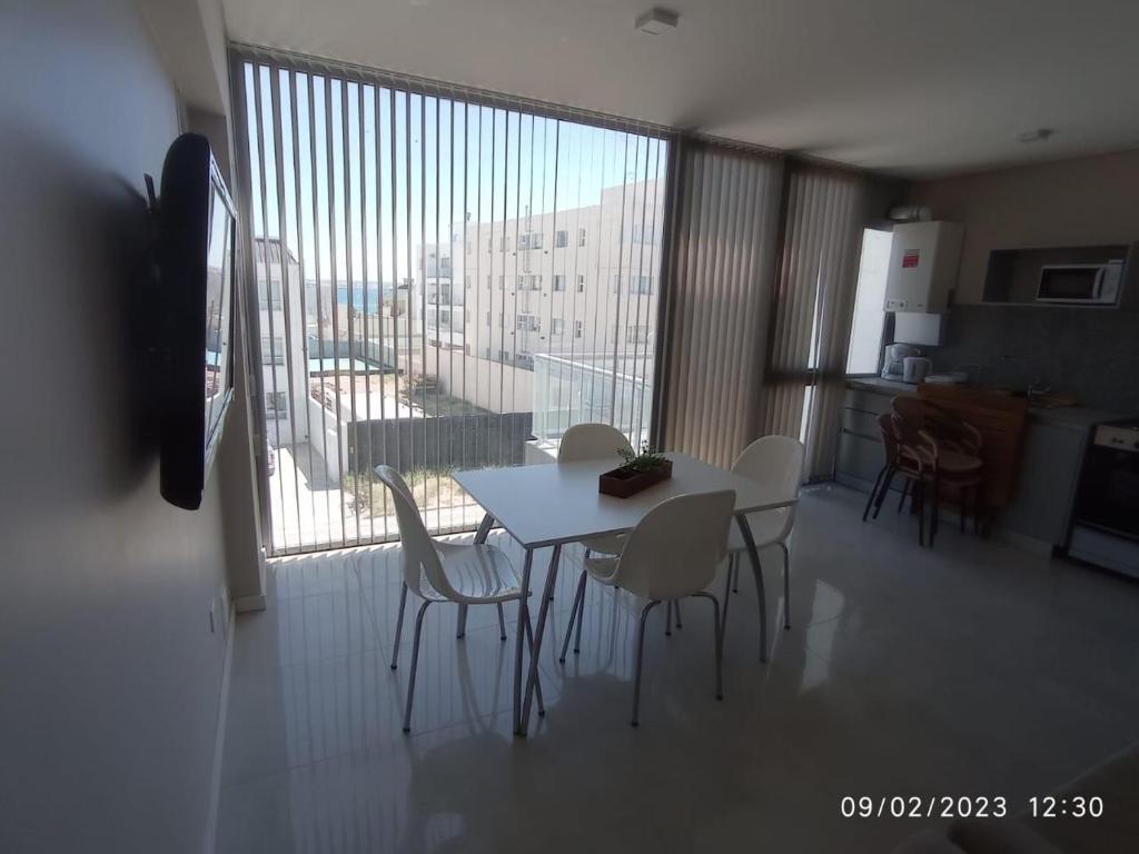 Habitación con mesa, sillas y ventana grande. en DEPARTAMENTO PUERTO MADRYN en Puerto Madryn