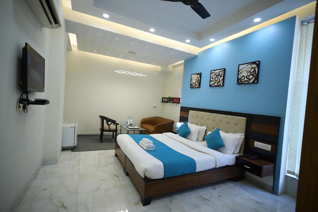 - une chambre avec un grand lit et un mur bleu dans l'établissement Asian Suites Cyber Park Gurgaon, à Gurgaon