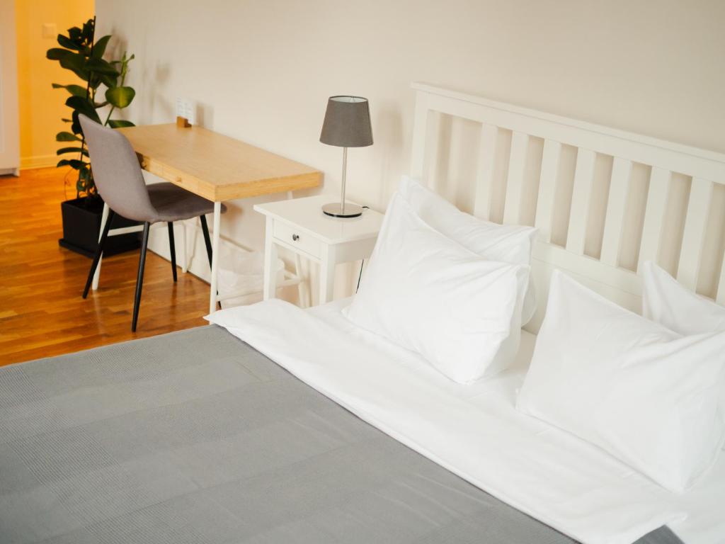 Schlafzimmer mit einem Bett mit weißen Kissen und einem Schreibtisch in der Unterkunft Danylo Inn in Lwiw