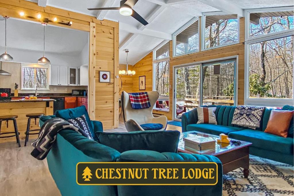 a living room with blue couches and a kitchen at Chestnut Tree Lodge - Modern Wooded Escape in Jim Thorpe