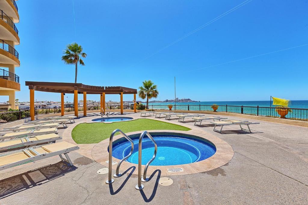 een resort met een zwembad en stoelen en de oceaan bij Sonoran SKY #910 in Puerto Peñasco