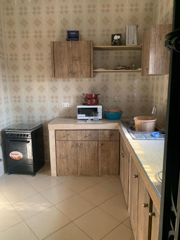 a kitchen with wooden cabinets and a microwave at Eric’s Apartment in Kasoa